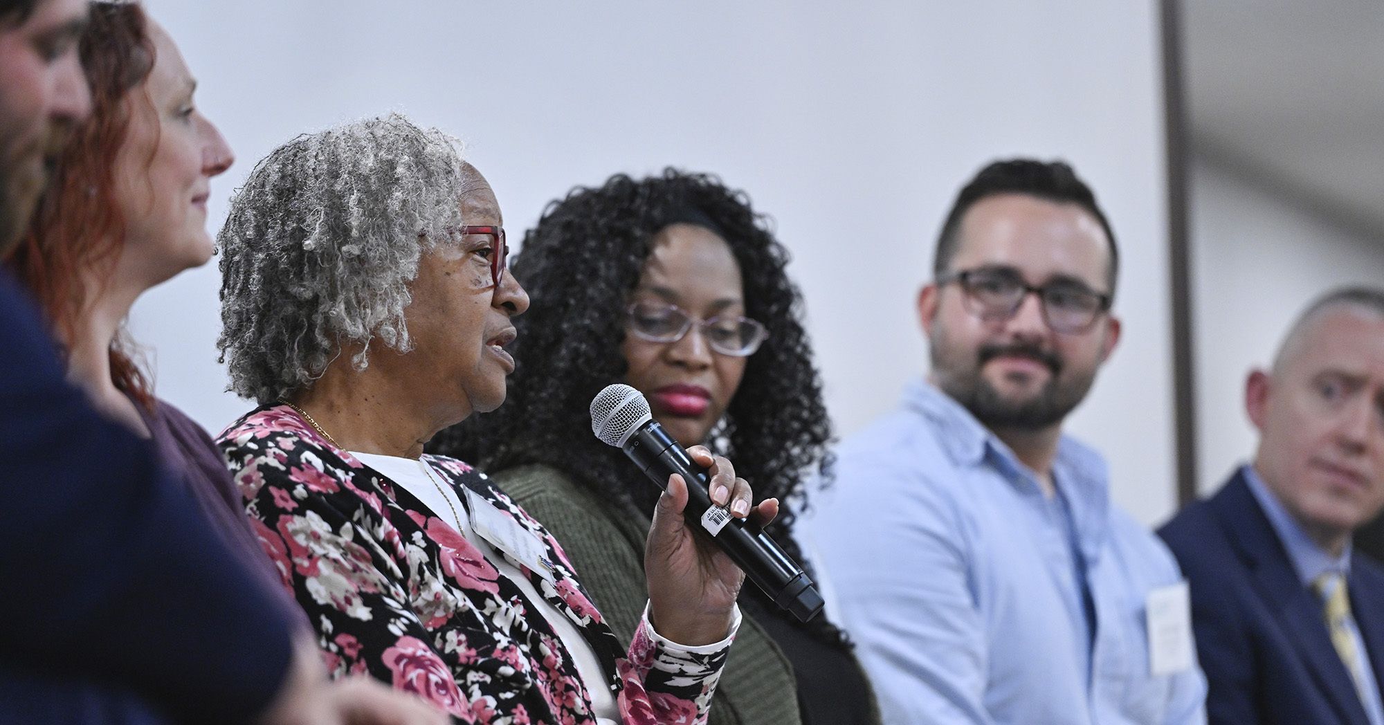 A row of diverse conference speakers talking into a microphone