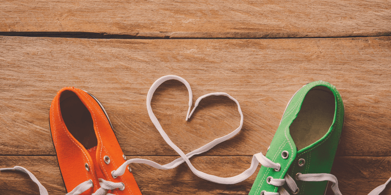 Two canvas shoes next to each other. Their laces forming a heart shape.