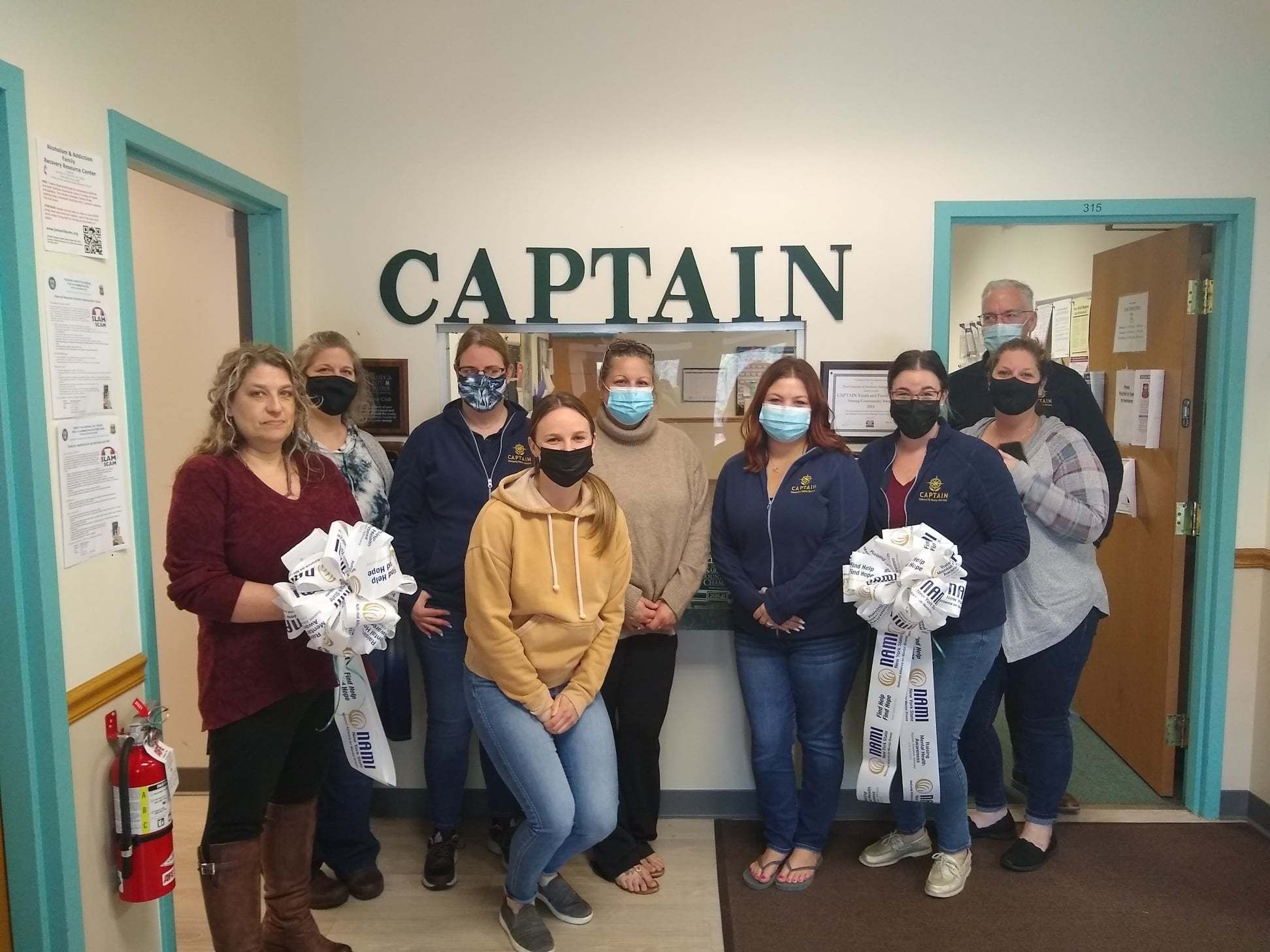 Staff at the Clifton Park office posing with ribbons from NAMI New York State which will be displayed in support of NAMI's mission and having a mentally healthy workplace!