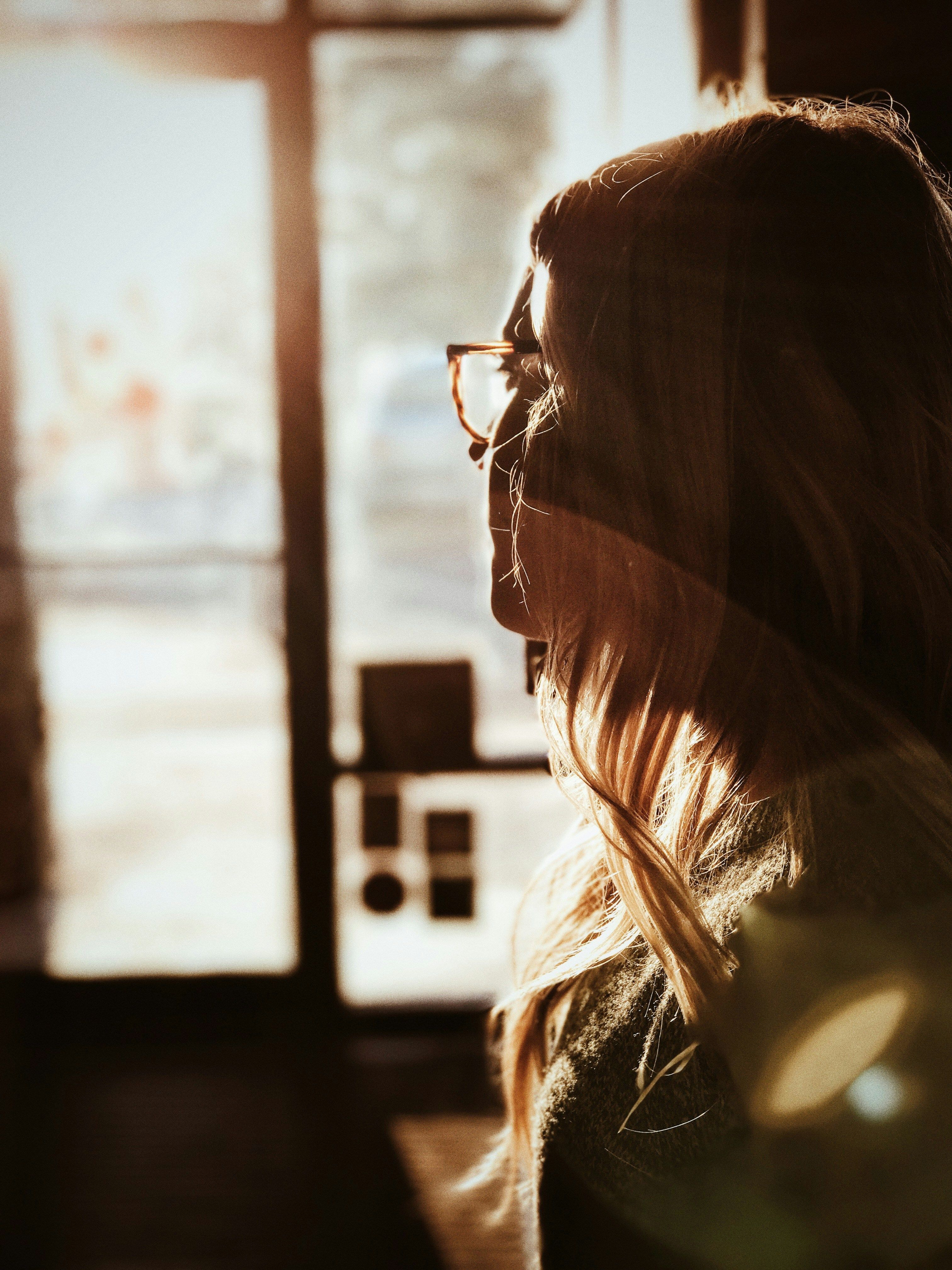 Photo of a woman looking out of the window in deep thought.
