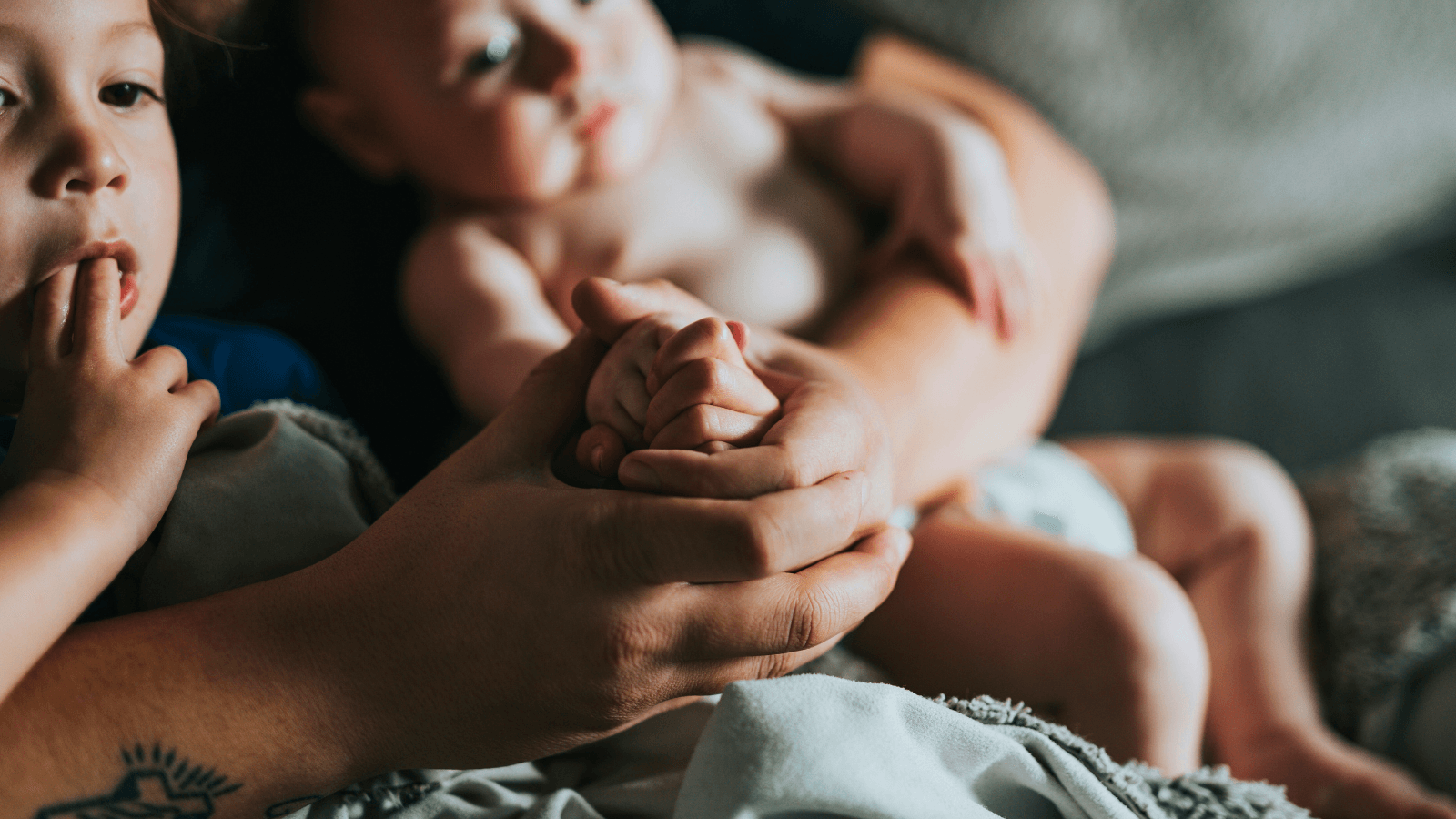 Parent holding infant and toddler on lap