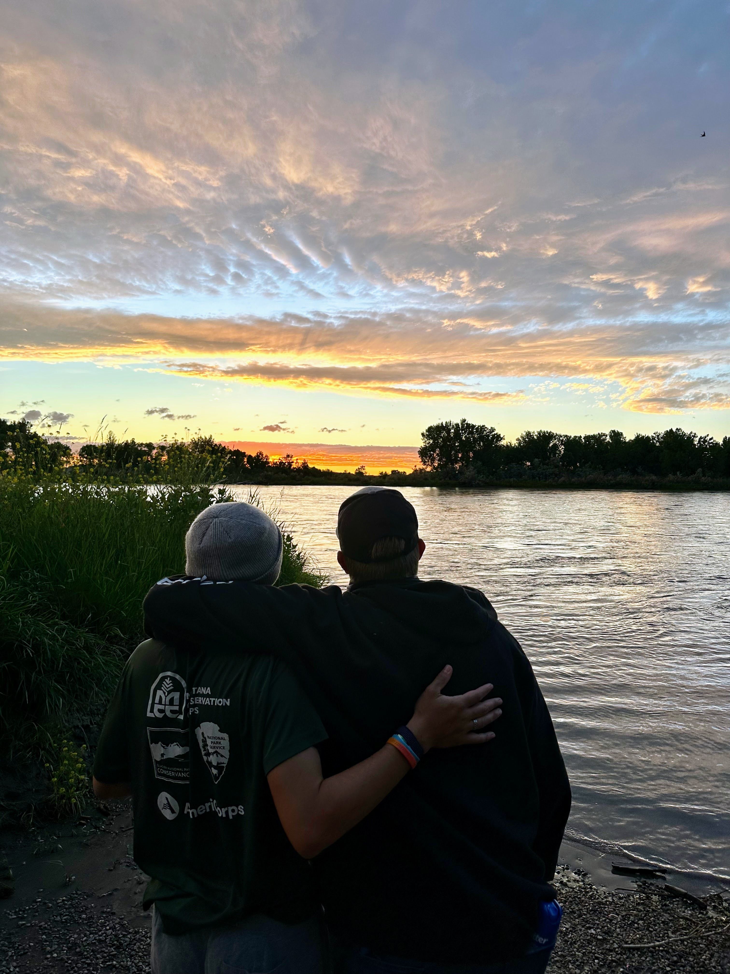 Two youth members face a sunset