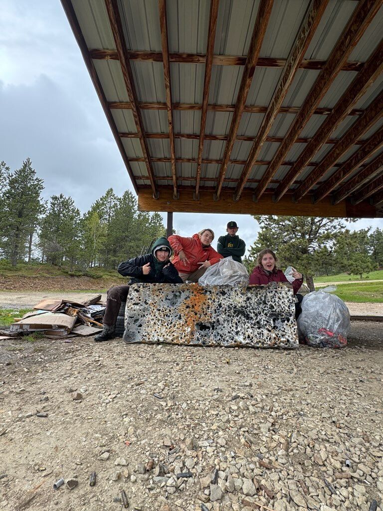 Crew members post around a large rock and trashbags