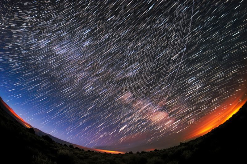 The trails of dozens of satellites interfere with the trails of hundreds of stars in this photograph.
