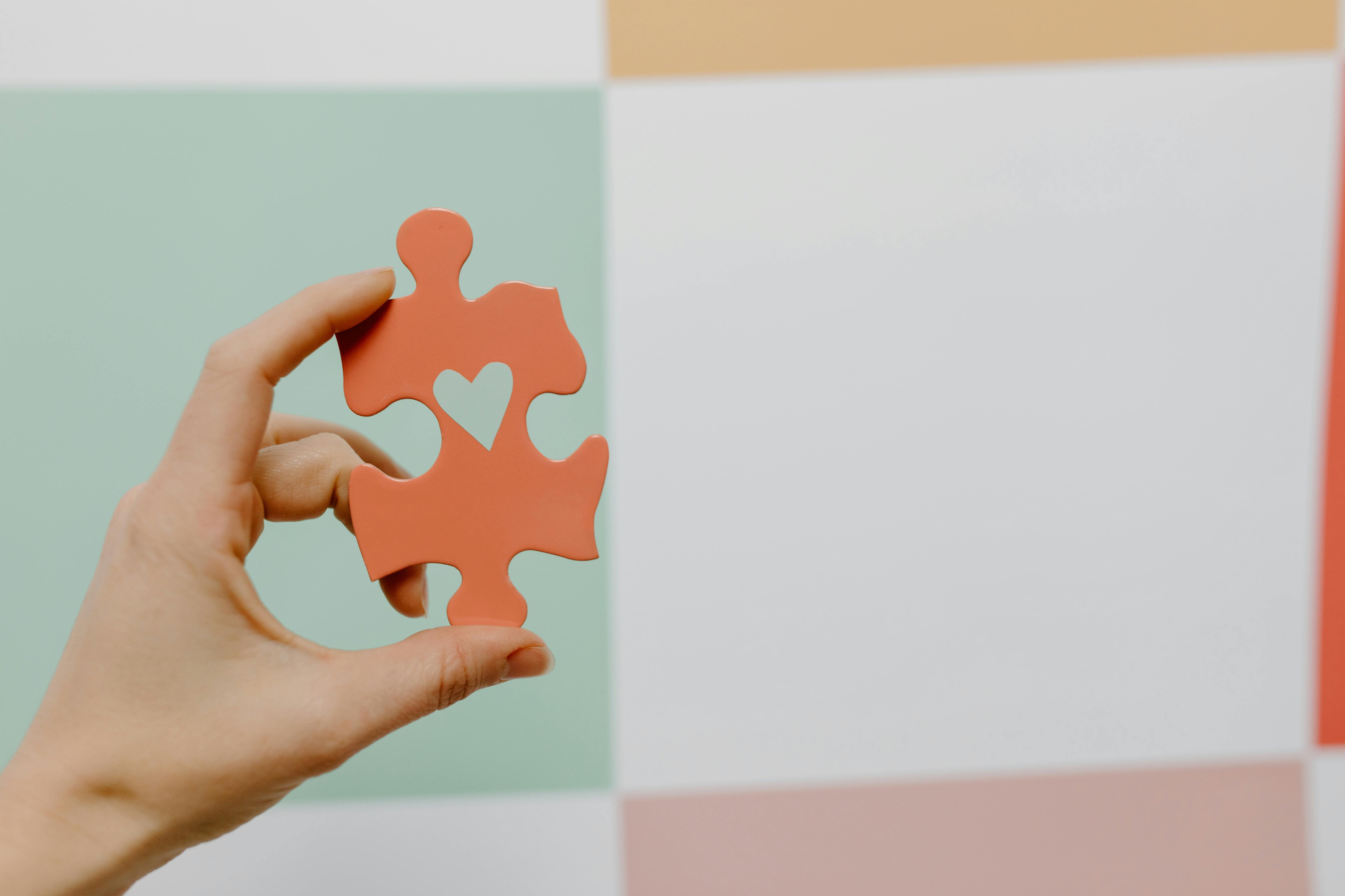 hand holding a puzzle piece with a heart cut-out