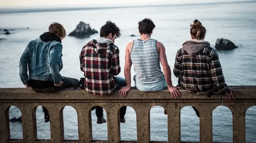 Four teenagers sit on a bridge overlooking the water