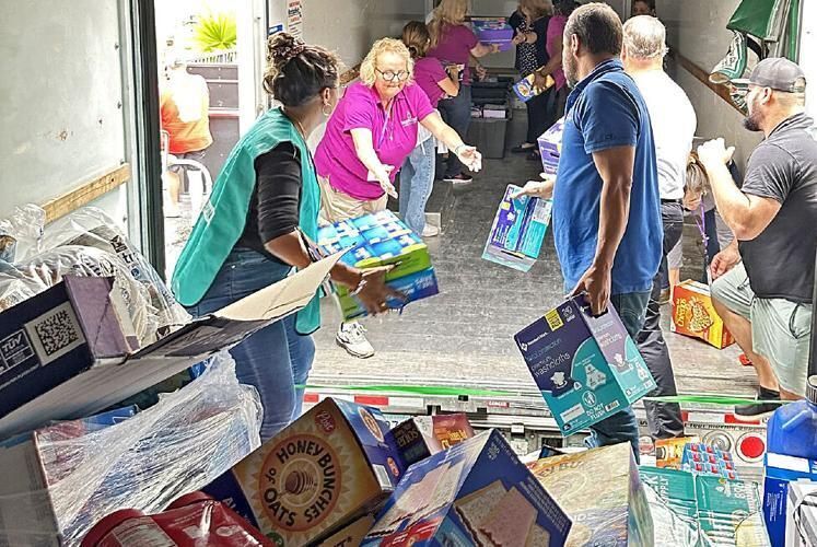 Staff and volunteers with Catholic Charities of the Diocese of Palm Beach help transfer donated goods from one truck to another for distribution to those in need.