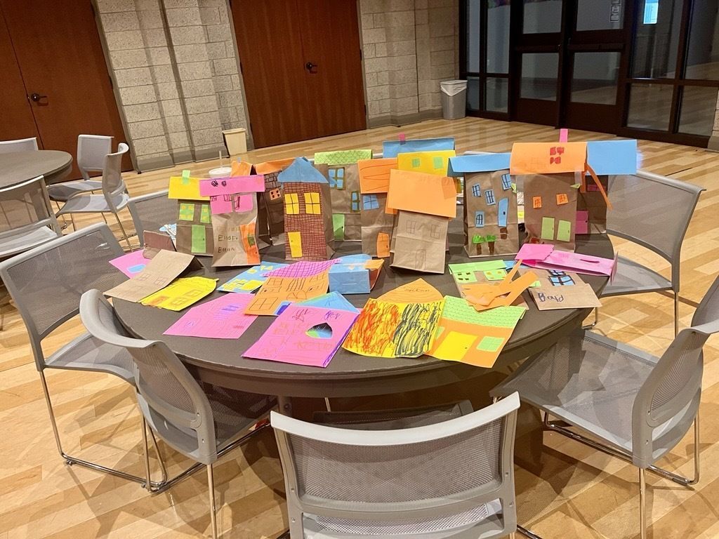 Colorful paper houses crafted by children spread across a table during a Habitat craft activity day at Clemson United Methodist Church.