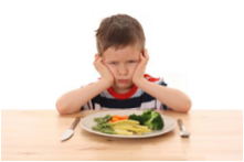 This is a picture of a boy who is unhappy about having to eat his vegetables