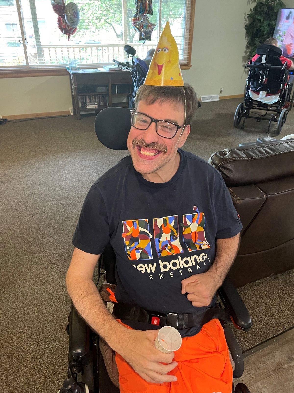 Man wearing a party hat smiles at the camera