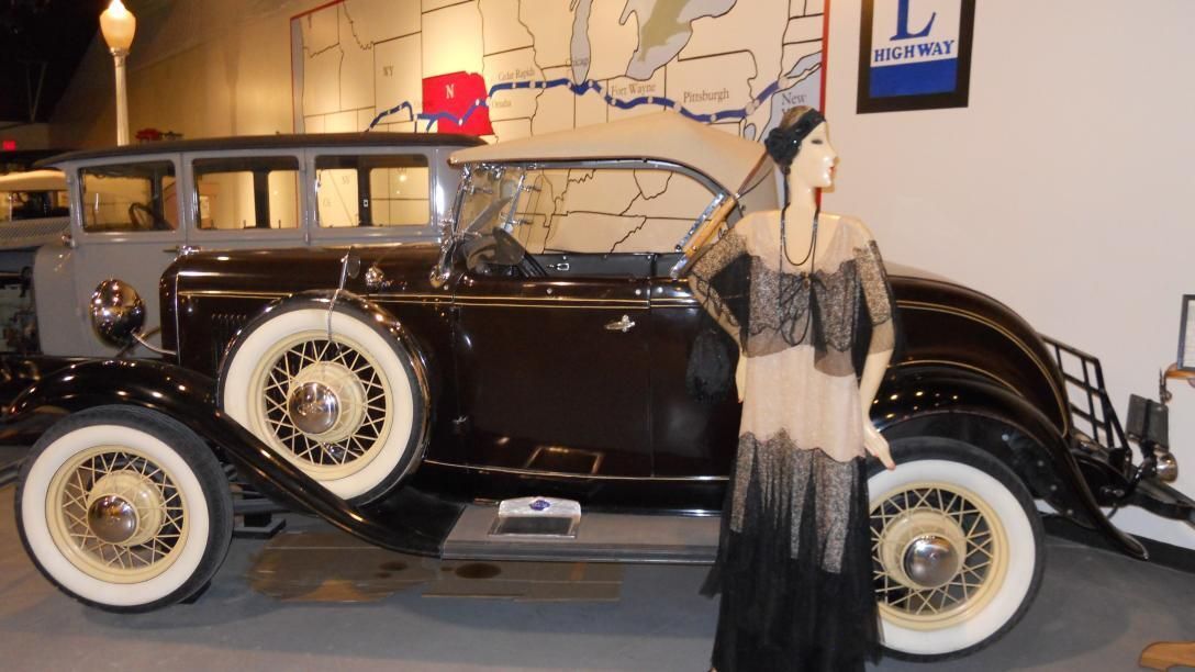 A vintage car and mannequin of a woman from the 1920s in an exhibit