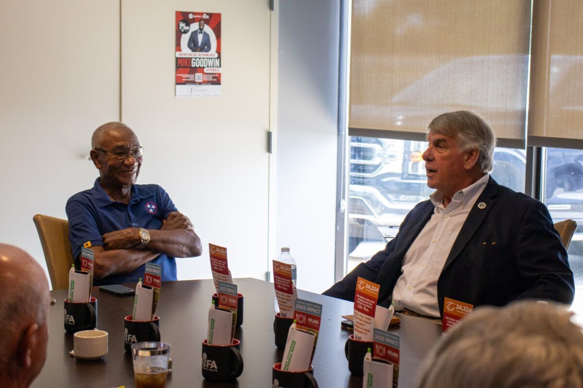 Two men sitting at a conference table talking.