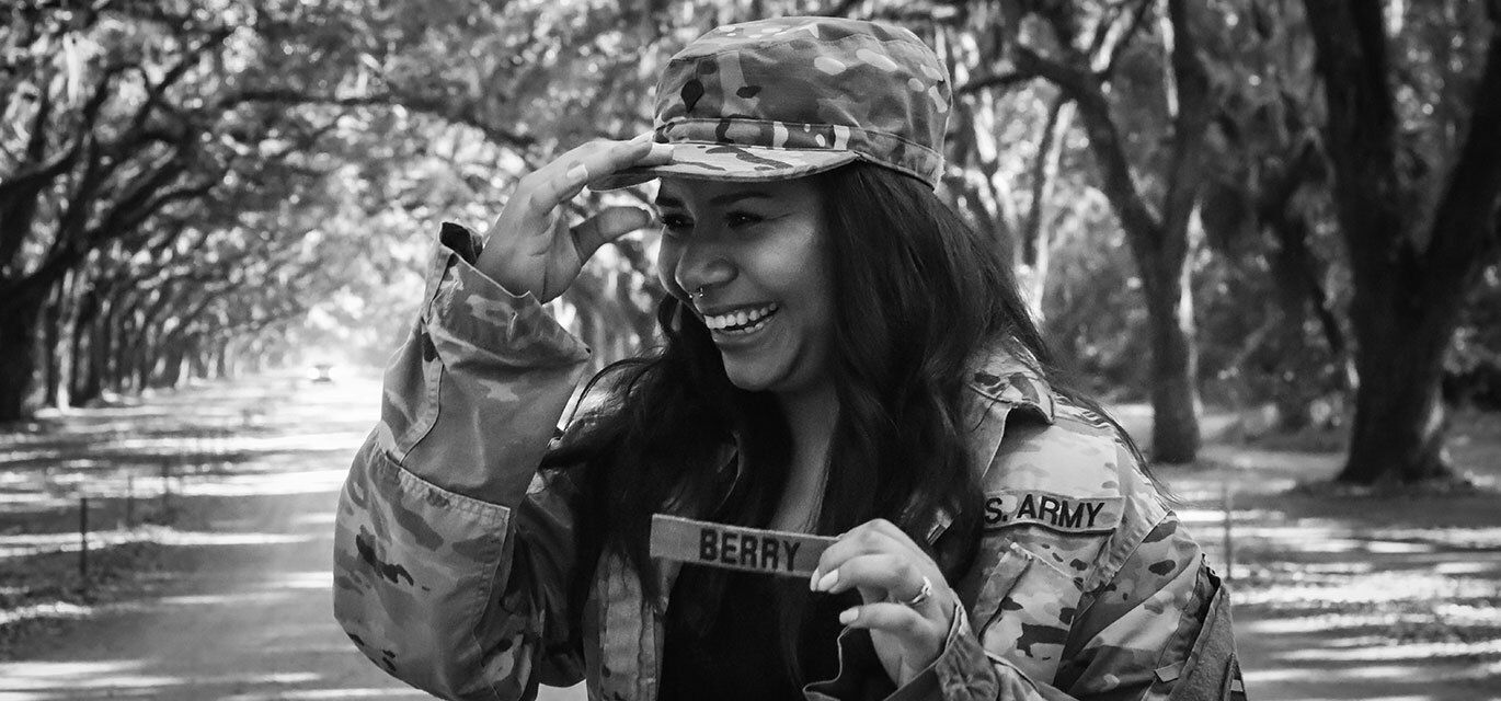 Woman in military uniform proudly holding her name tag.