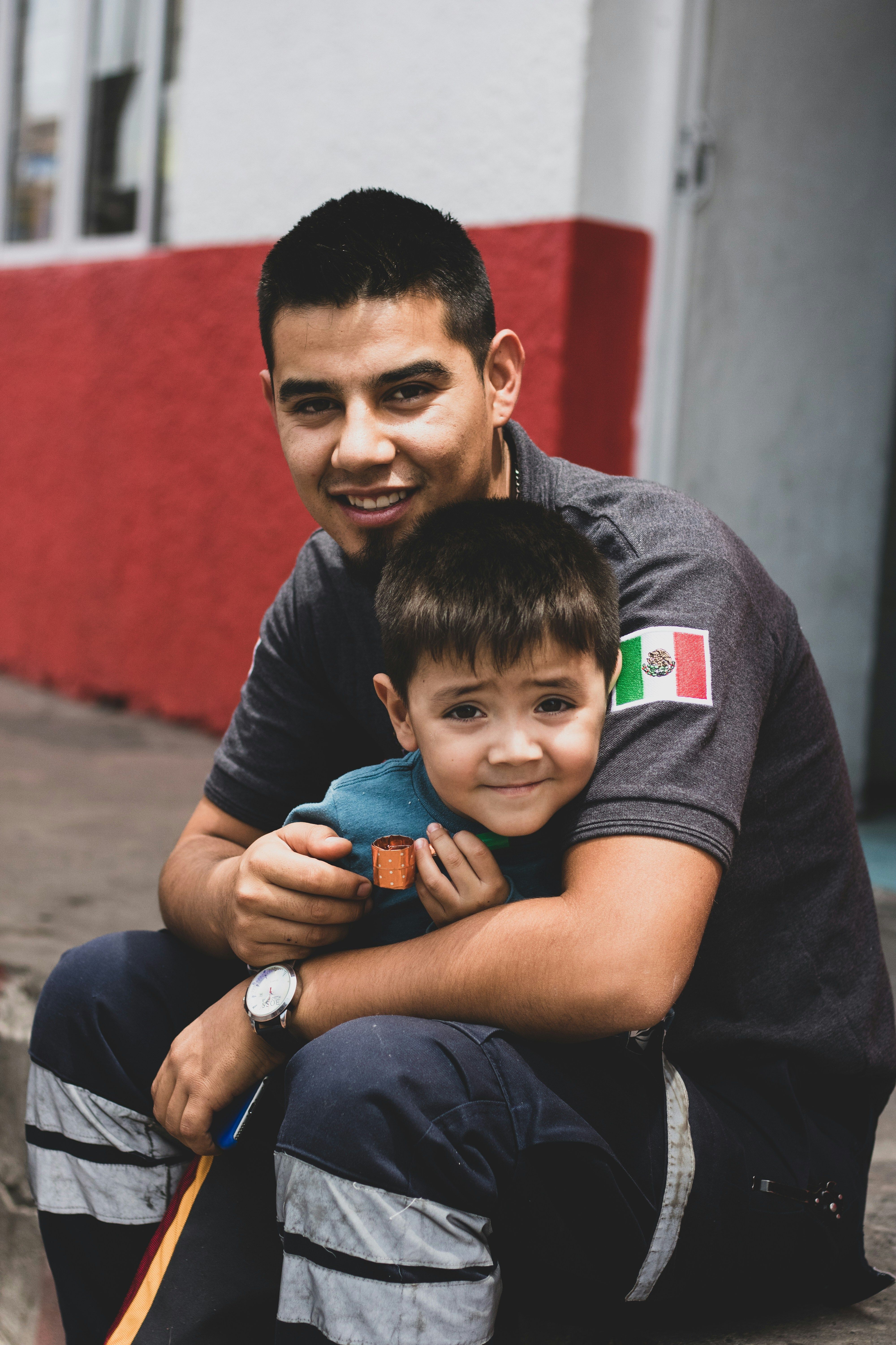 A group of smiling people holding flags from Mexico and Central American countries