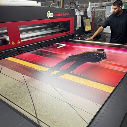 A large-format printer producing a vivid, colorful print as a person oversees the process.