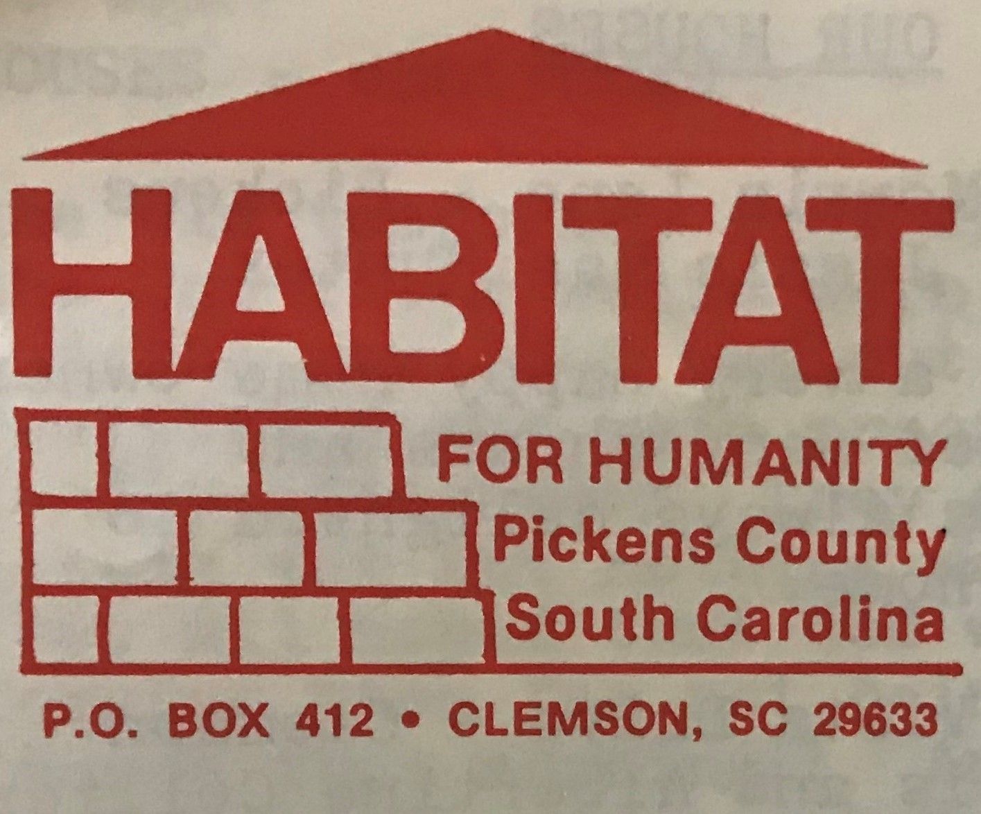 A red vintage Habitat for Humanity logo made of illustrated bricks and a roof.