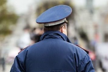 Police officer standing in front of police car. 