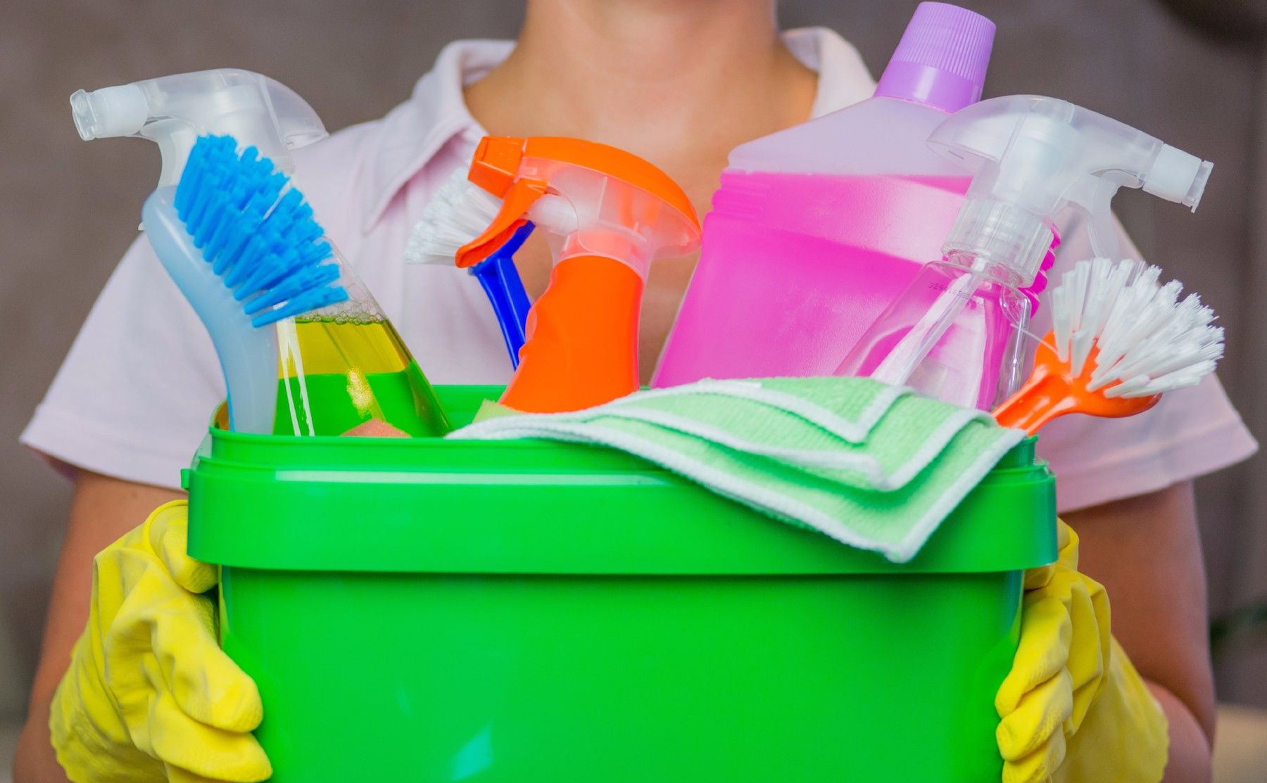 woman holding a bucket full of spring cleaning supplies