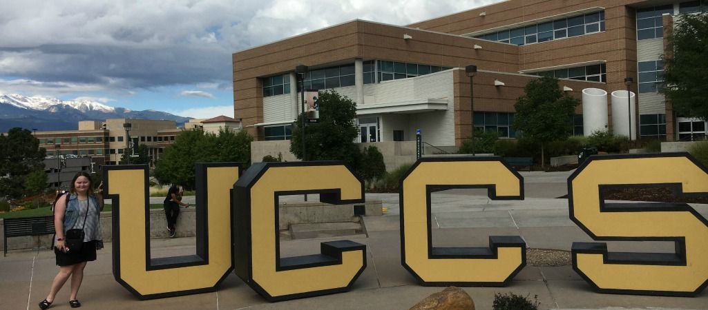 Student with down syndrome poses with UCCS sign on campus