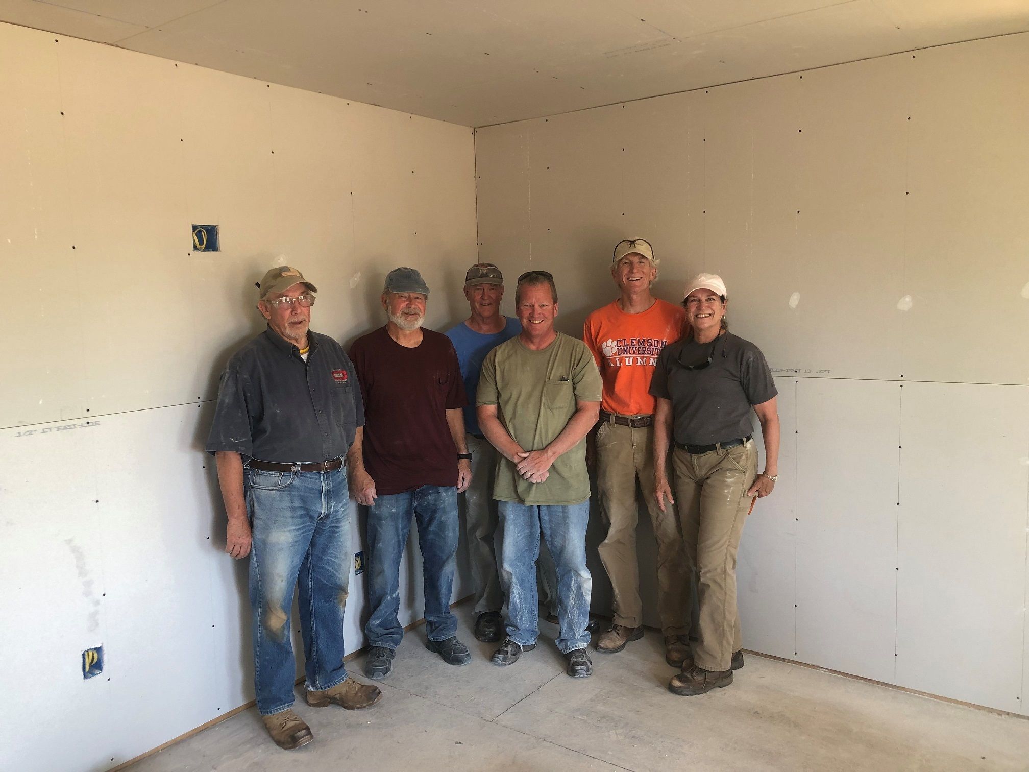 Tuesday/Thursday crew members pose together inside of a Habitat house under construction