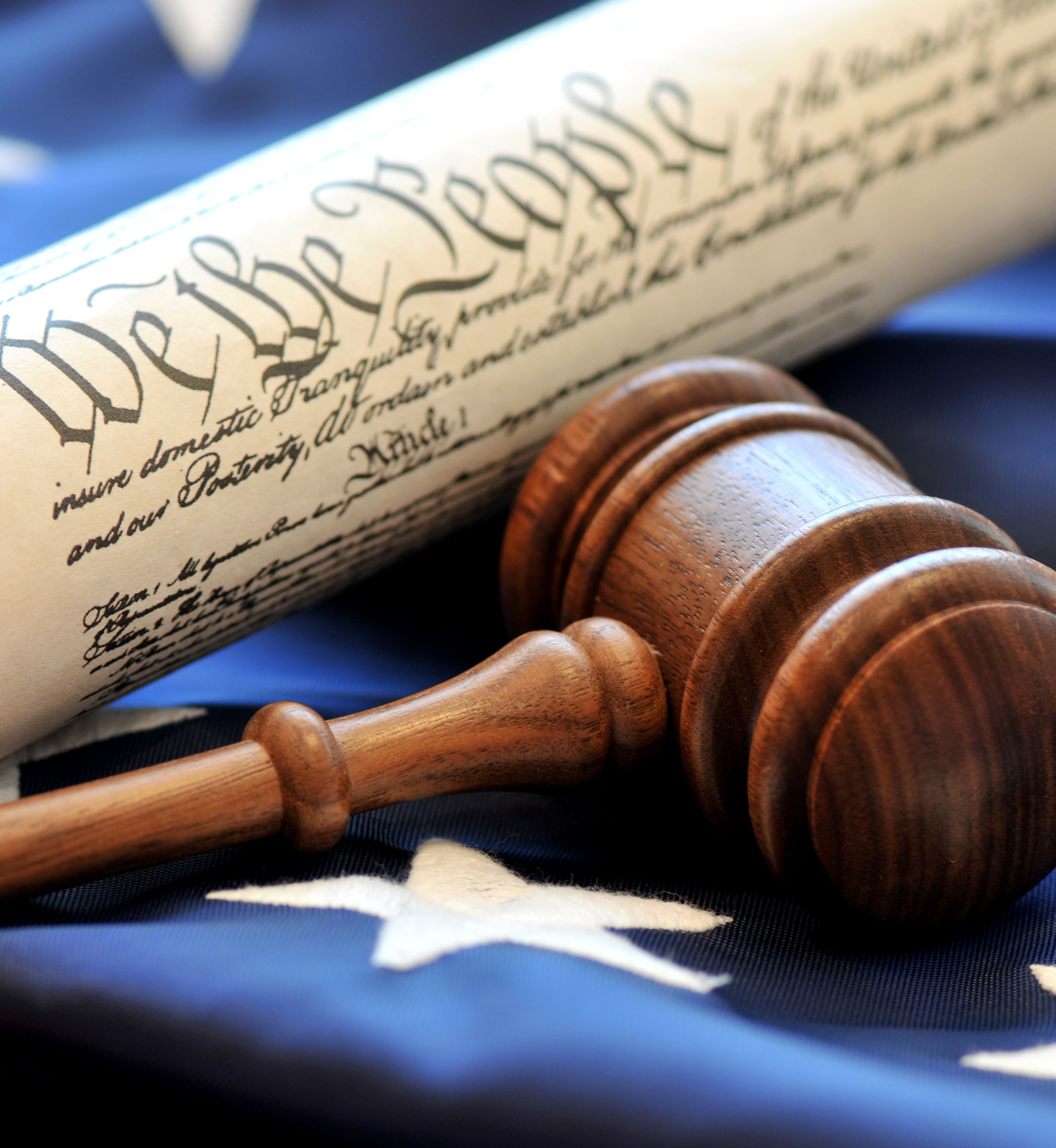 A judge's gavel lies next to a printed scroll of the U.S. Constitution