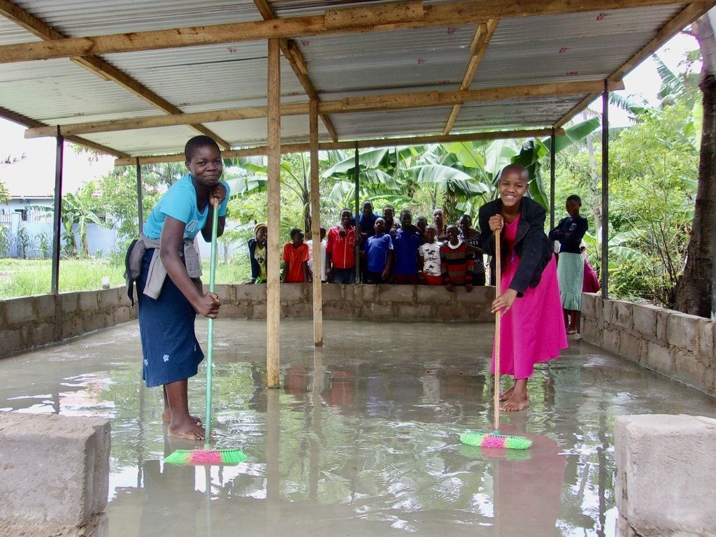 Two women cleaning the floors at their school.