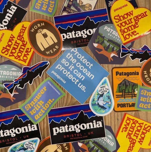 Collection of Patagonia branded stickers scattered on a wood table, demonstrating sticker marketing through outdoor brand messaging.