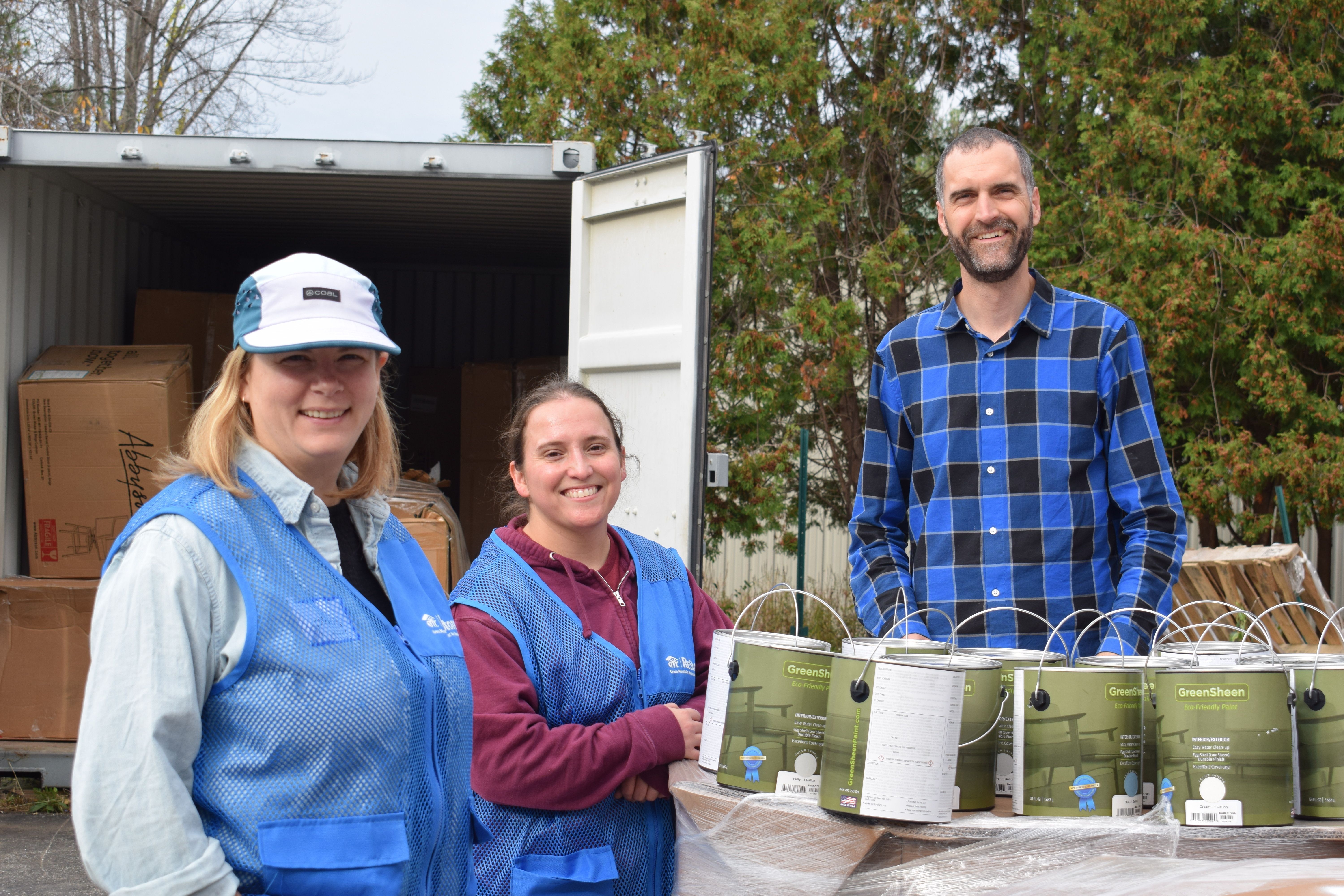 Volunteers smile while helping with paint.