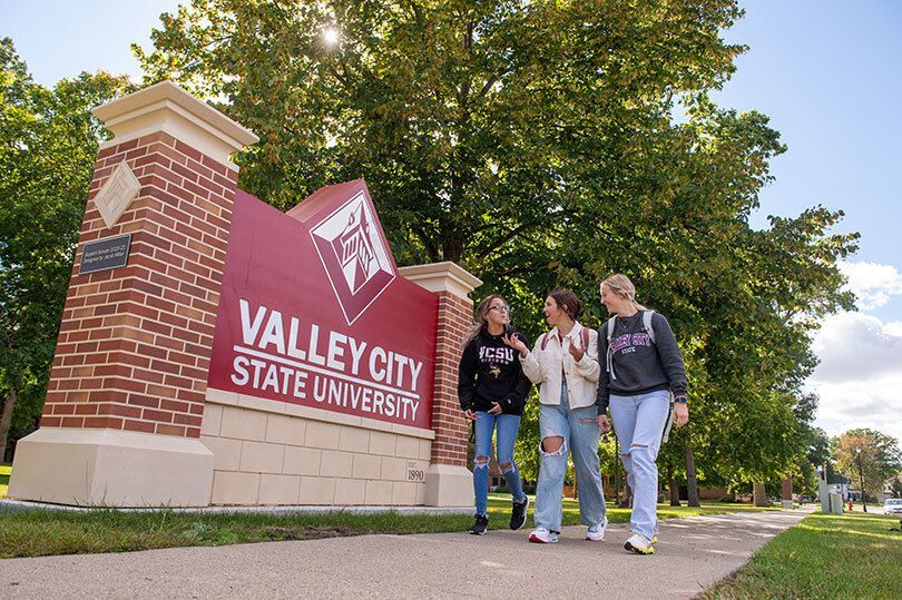 Students walking in front of the main VCSU sign, engaged in conversation
