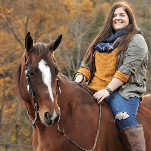 Tasha Hardinger smiling atop a brown horse.
