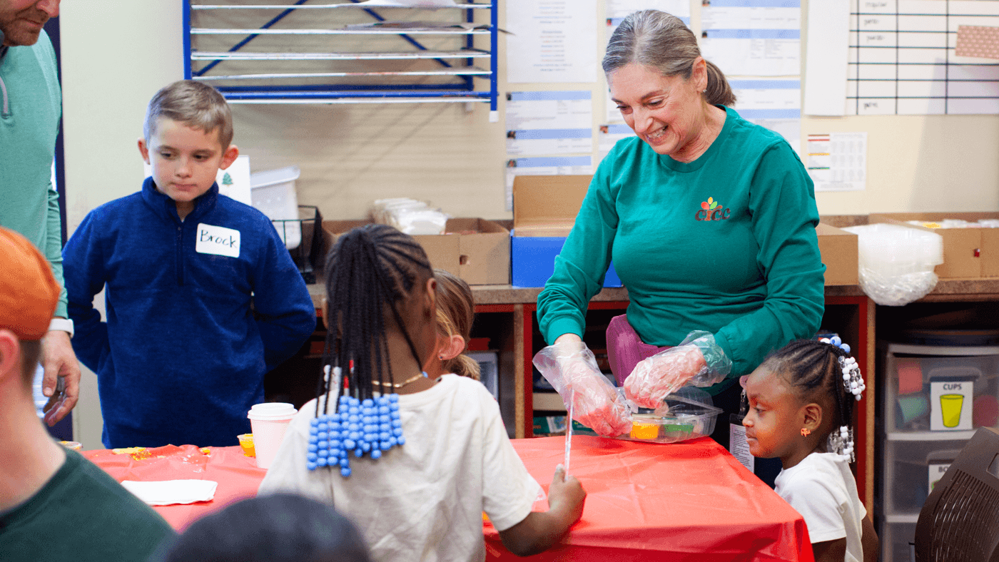 Staff member volunteering at our holiday party and helping kids decorate cookies