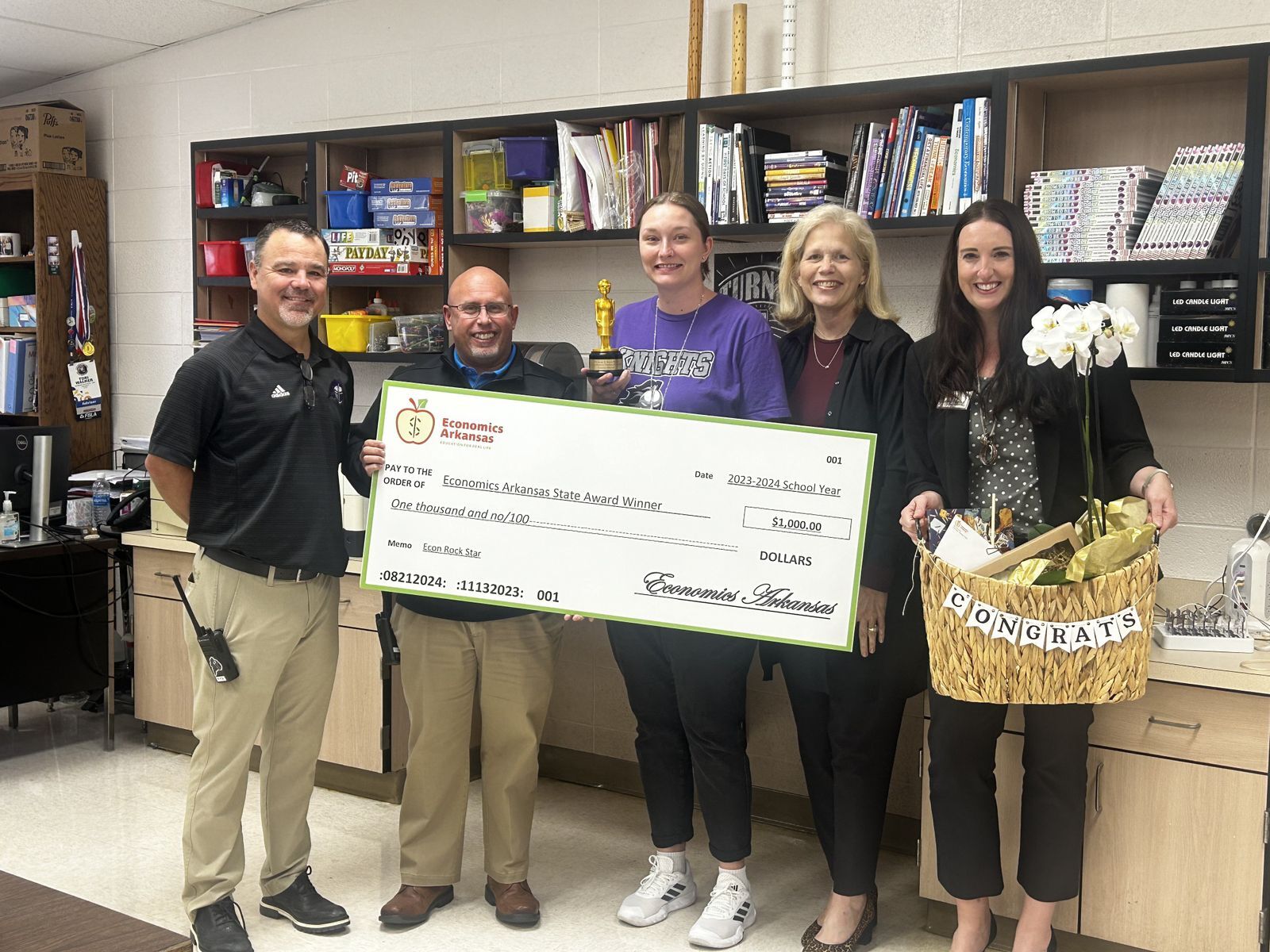 group of adults presenting large check and award to teacher