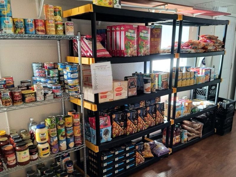 Photo of food pantry shelves, lined with canned goods, cereals, and other shelf-stable food.