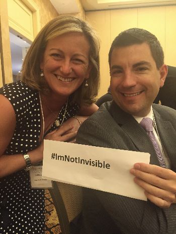Photo of Carol Brill and Dr. Mark Pennesi holding a sign that reads #ImNotInvisible