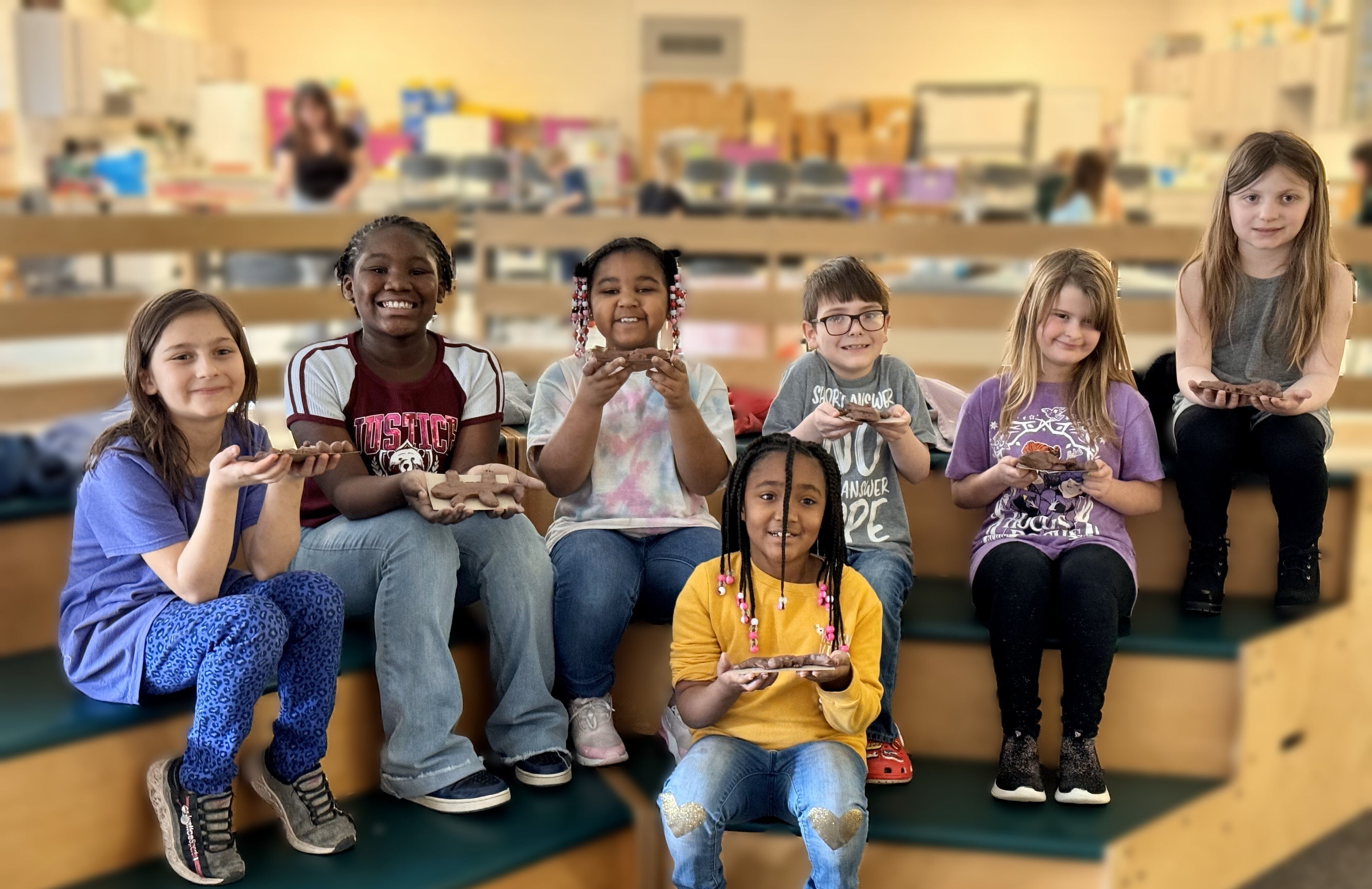 Smiling students displaying their clay sculptures of the Hellbender