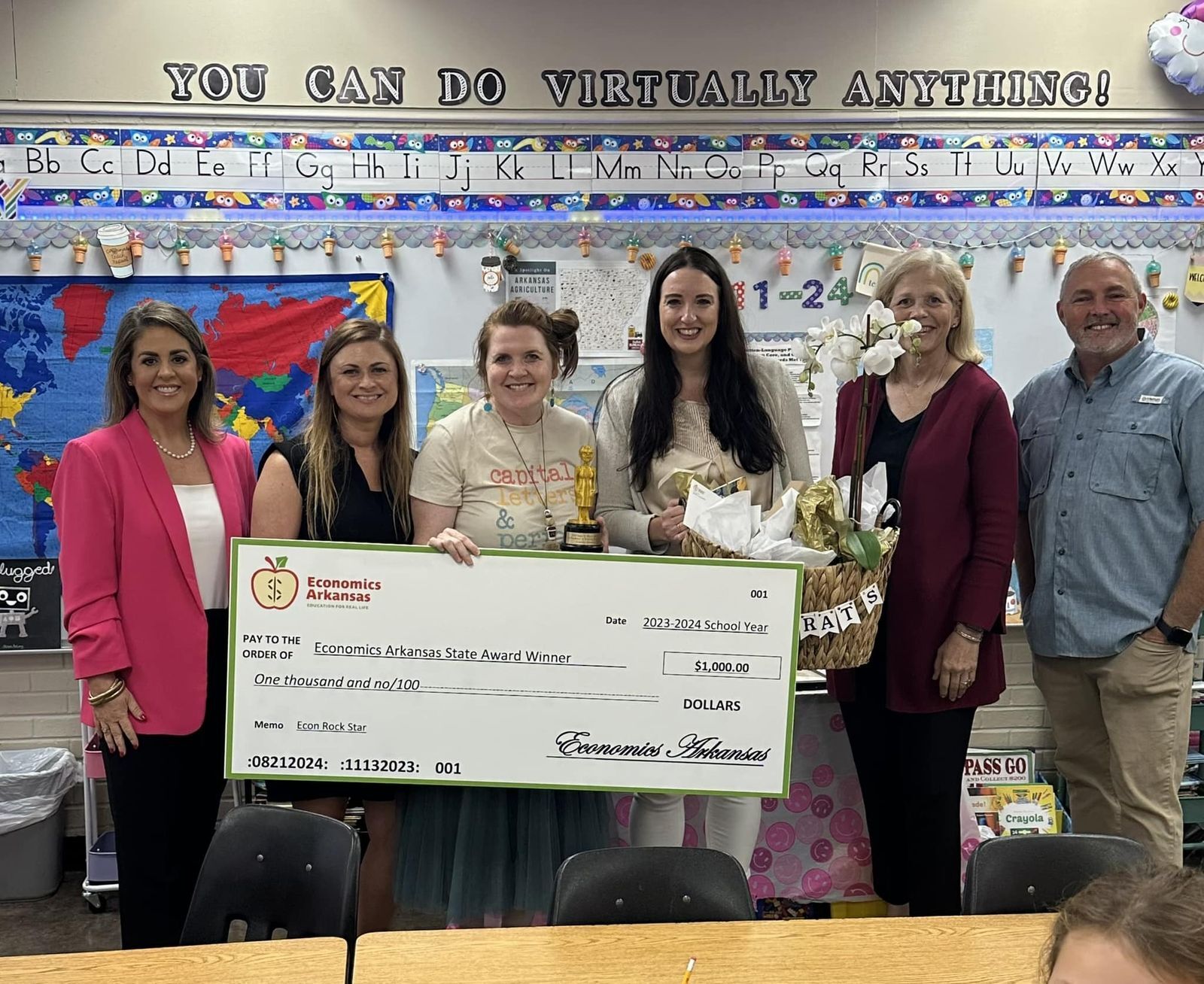 group of adults presenting large check and award to teacher