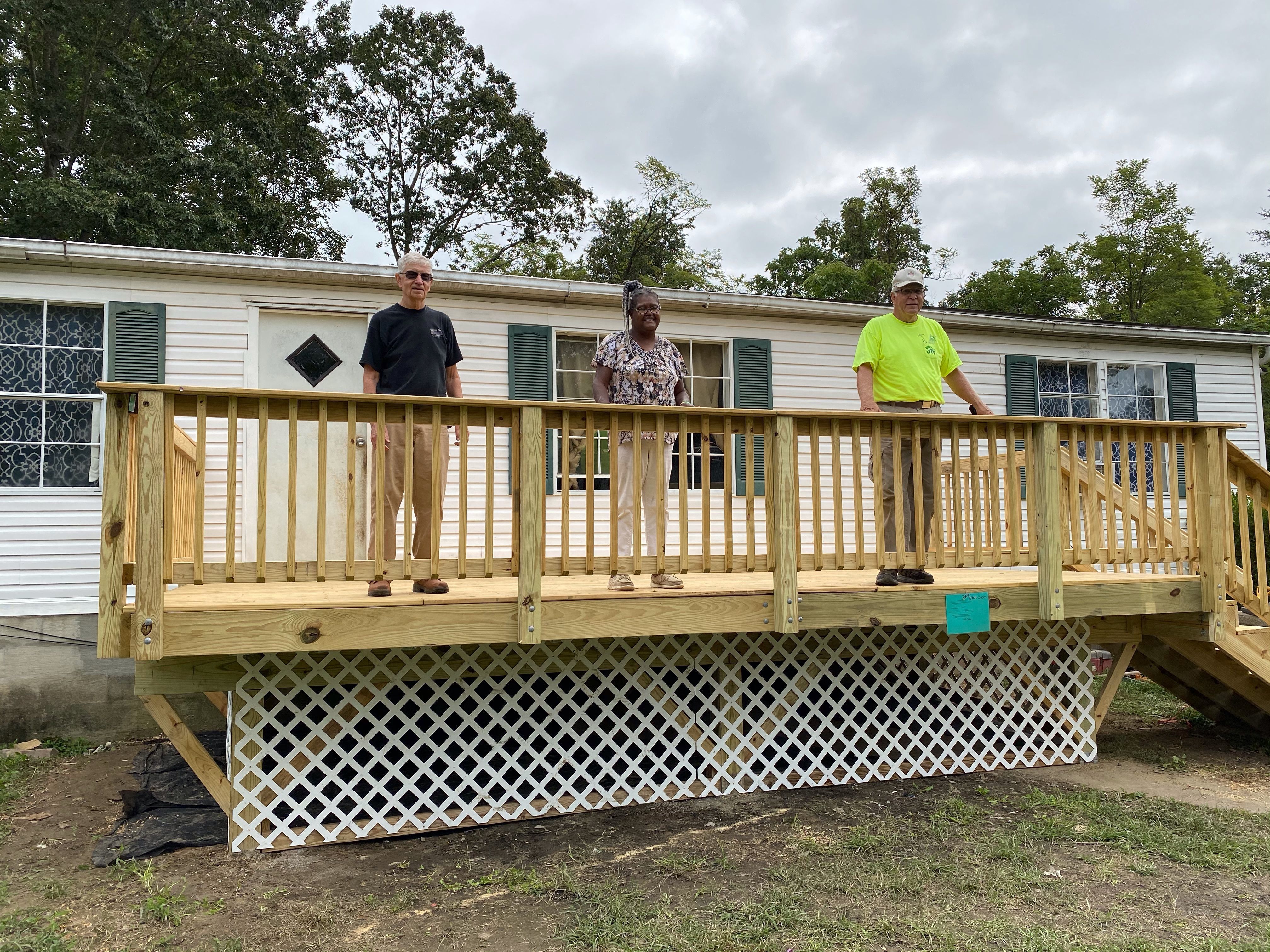 Three people standing on a newly repaired deck.