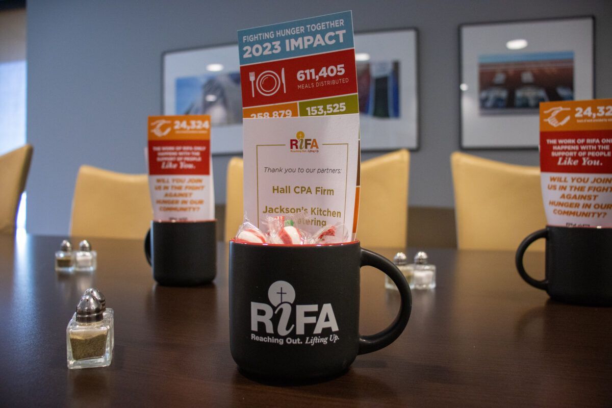 Black mugs with RIFA logo on a conference table, filled with candies and informational cards.