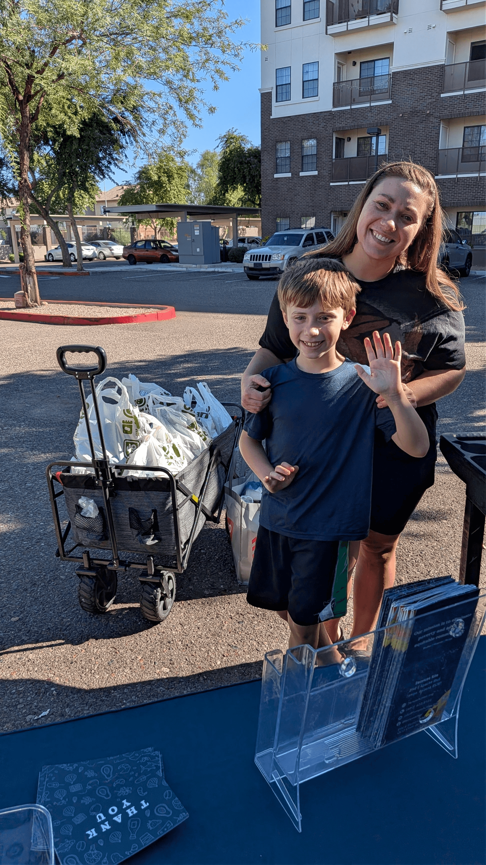 Mother and son next to a wagon of food donations