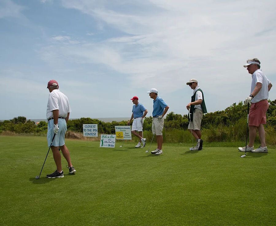 Group of men preparing to tee off during a golf tournament.