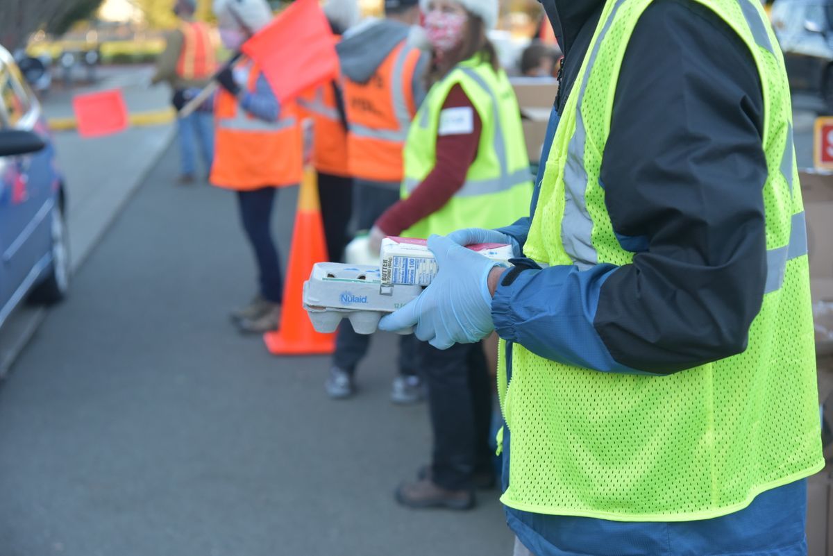 Volunteers holding food and waiting for cars at a distribution site
