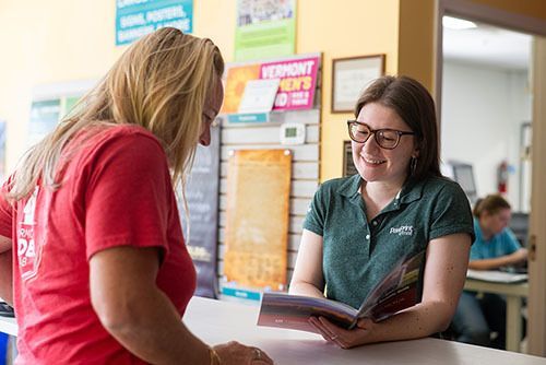 Two women standing at counter looking at printed booklet