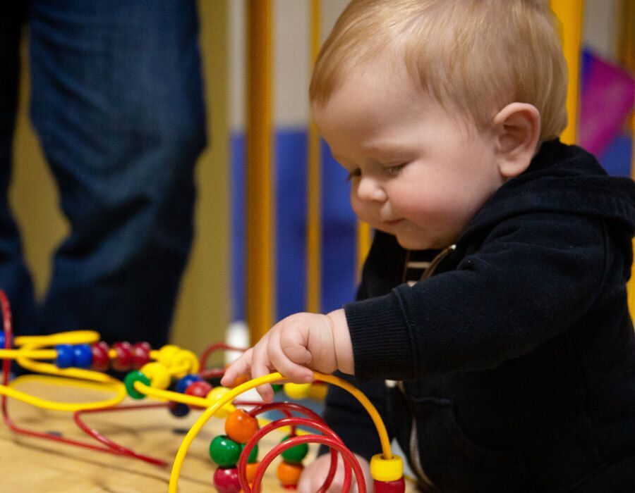 A young child playing with a colorful bead maze toy.