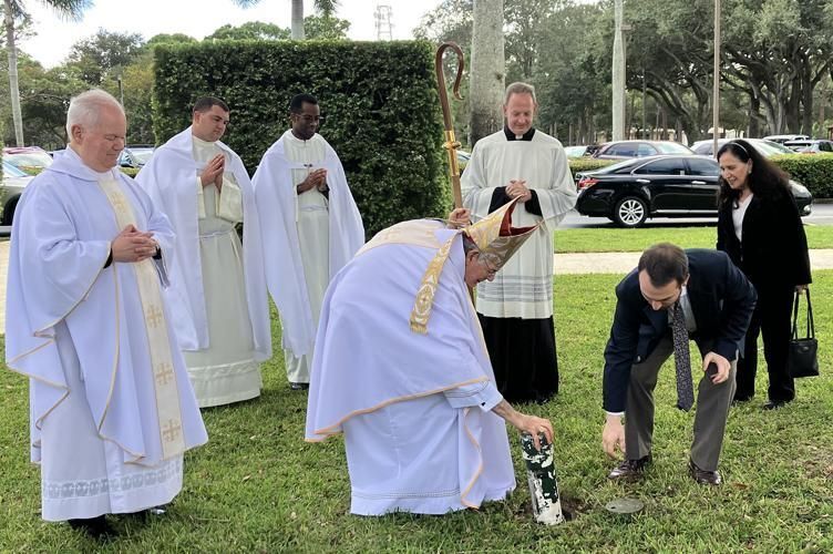 Bishop Gerald M. Barbarito, assisted by Hunter Ernde, director of development and public relations at St. Vincent de new scroll into the ground on the seminary campus