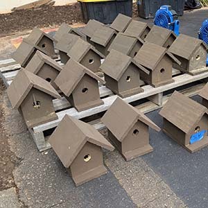 Rows of painted brown birdhouses lined up on a wooden pallet