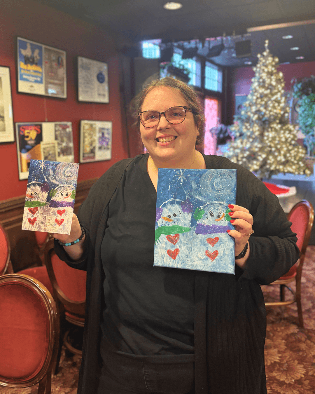 Vocational participant posing with her snowman painting turned into a greeting card.