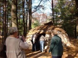 People viewing a wood hut on a historical tour.
