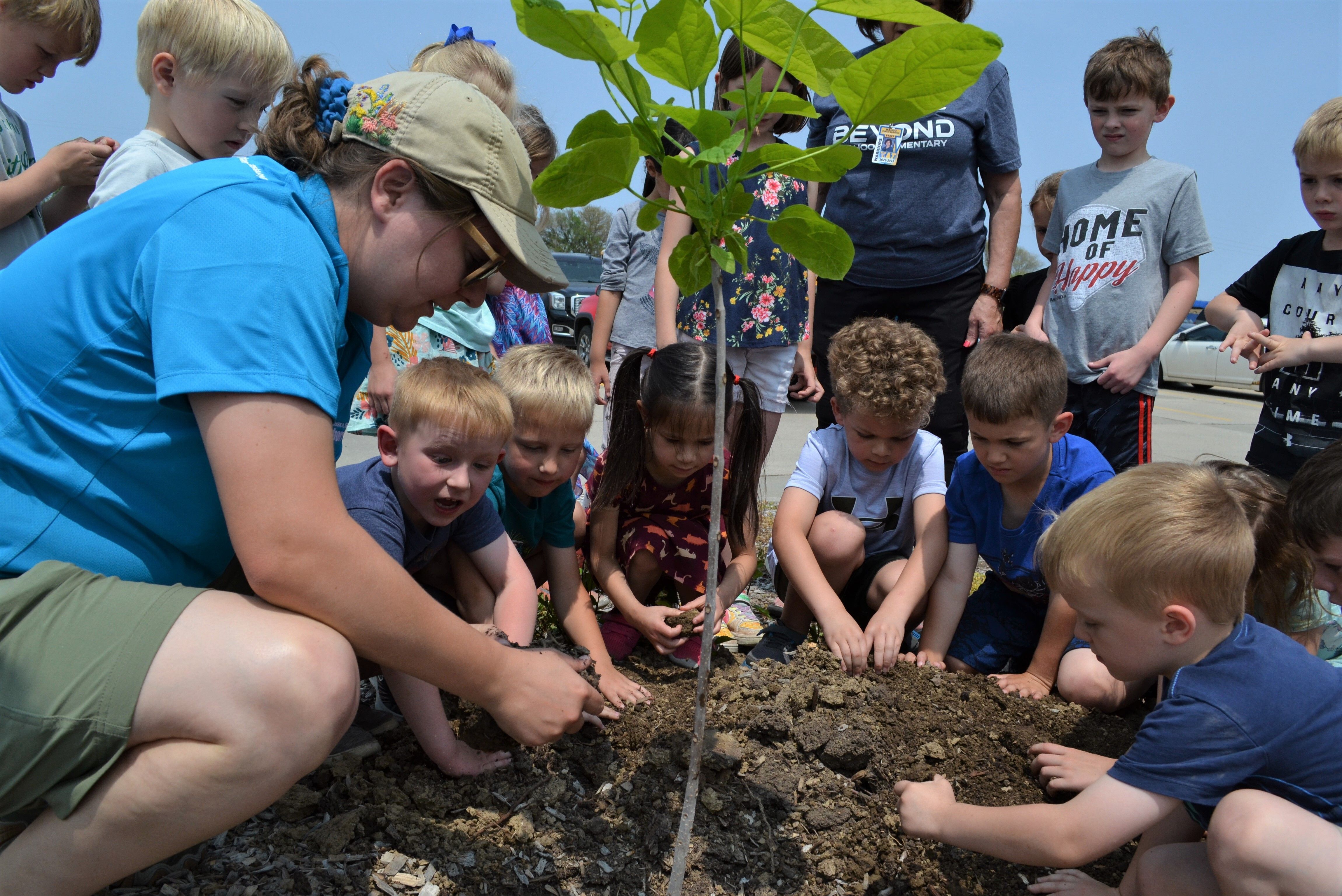NSA Sustainable Landscape Coordinator Sarah Buckley helps kindergarteners at Wahoo Elementary plant a Northern catalpa tree. 