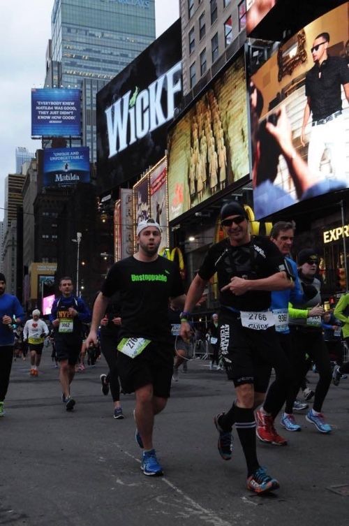 Photo of Brian running with his sighted guide, Marco on a tether in Times Square