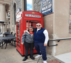 Bernice and Lenny in front of a telephone booth.